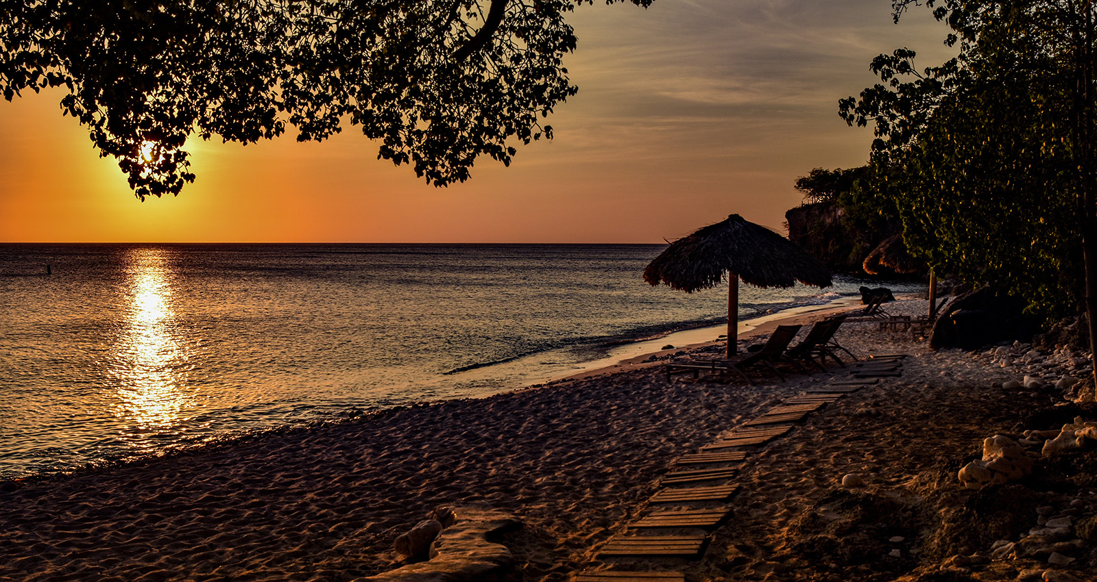 sunset at the beach in the caribbean a beach with chairs and umbrellas Caribbean